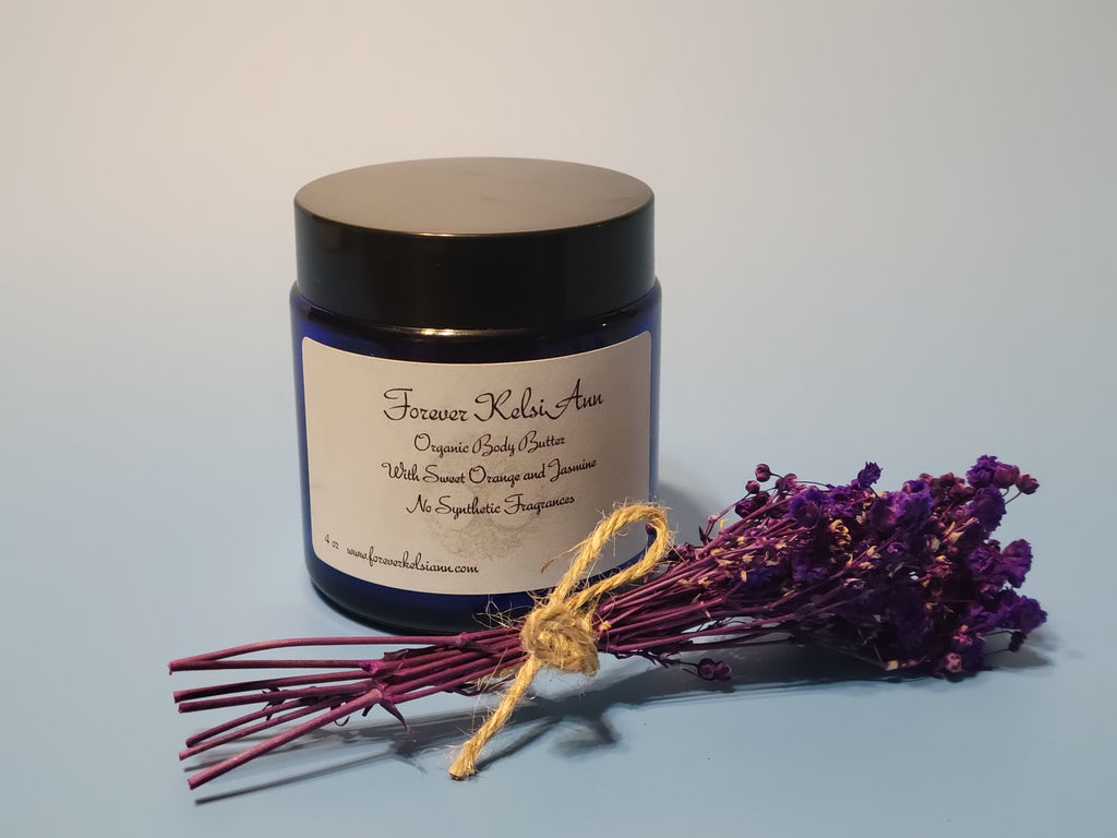 Jar of Forever Kelsi Ann organic body butter with a bundle of purple flowers on a light blue background